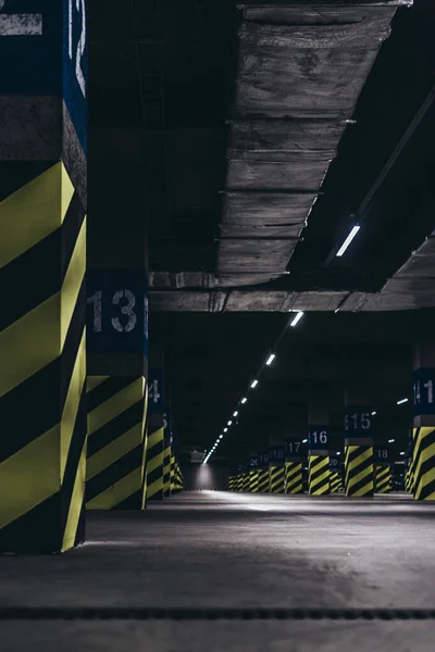 Süpermarketin altındaki yeraltı otoparkı, yeşil siyah çizgilerle boyanmış direkler.