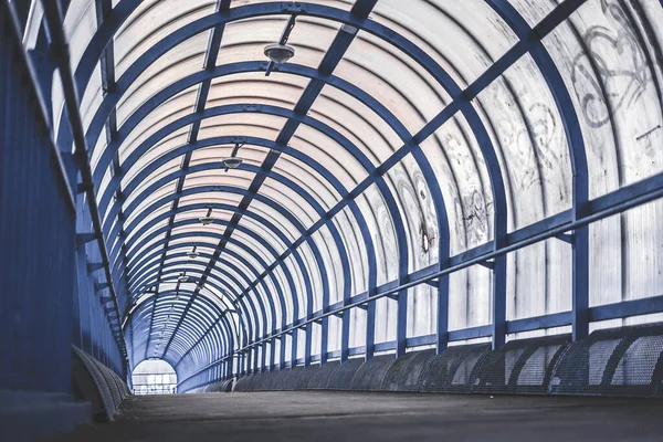 Şehrin tepesinde yaya geçidi var. Işık plastik camlardan geçer, metal maviye boyanır.