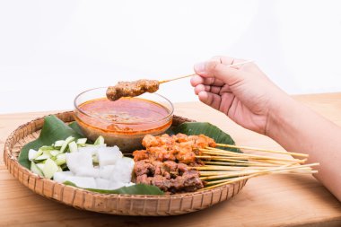 Malzemelerle geleneksel rattan tabakta satay tutan el