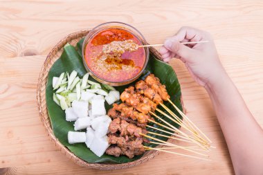 Malzemelerle geleneksel rattan tabakta satay tutan el