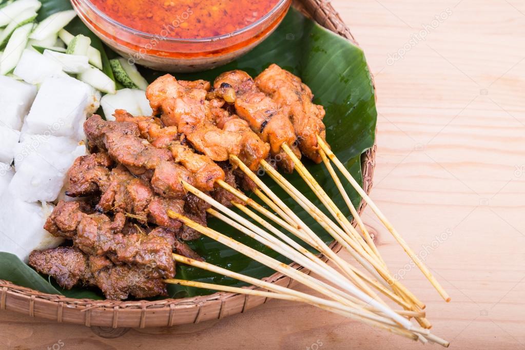 Barbacoa satay servida en plato tradicional de ratán con hoja de