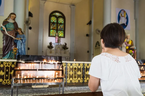 Crente se ajoelhar e orar em uma igreja católica — Fotografia de Stock