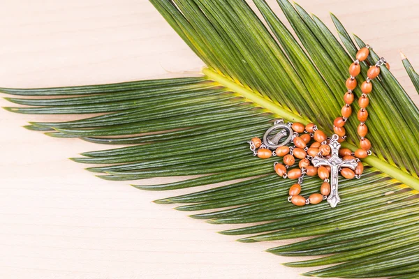 Closeup Catholic rosary with crucifix and beads on palm leaf — Stock Photo, Image