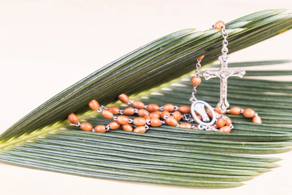 Closeup Catholic rosary with crucifix and beads on palm leaf — Stock Photo, Image
