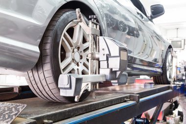Otomatik tekerlek hizalama geçiren aligner ile sabitlenmiş lastik closeup