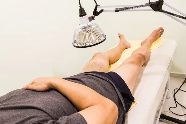 Patient souffrant d'acupuncture traité avec des aiguilles et une lampe thermique infrarouge — Photo