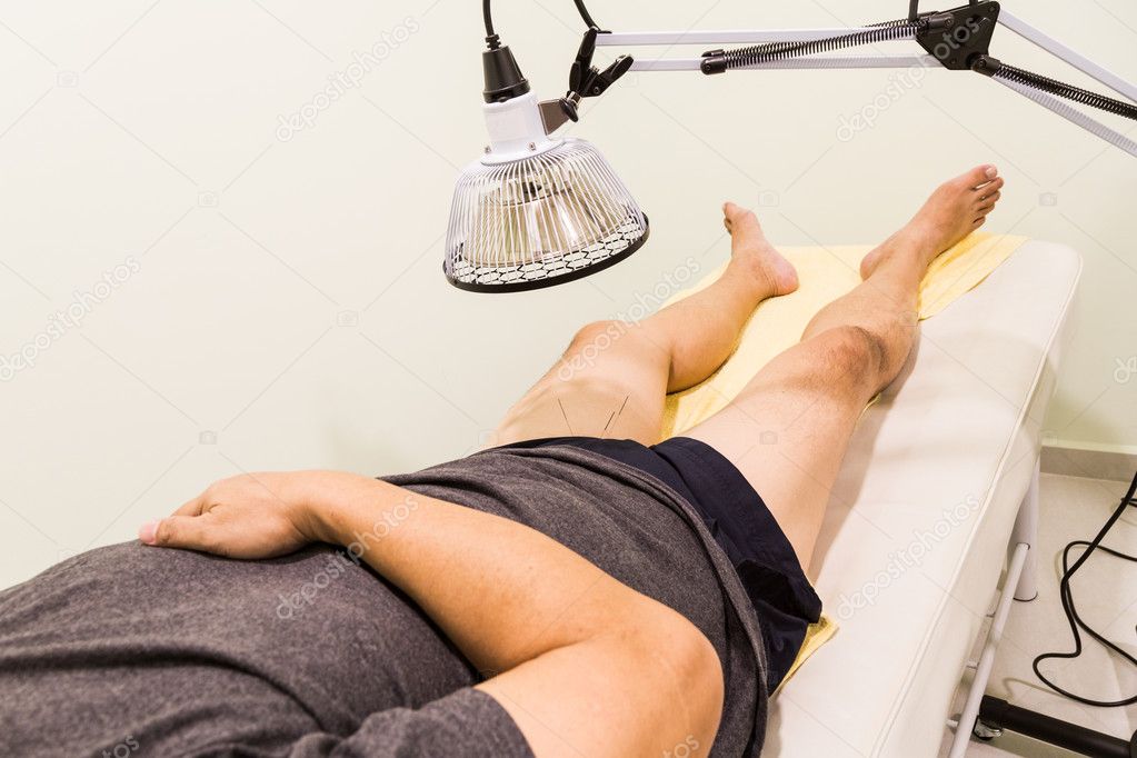 Acupuncture patient being treated with needles and infrared heat lamp