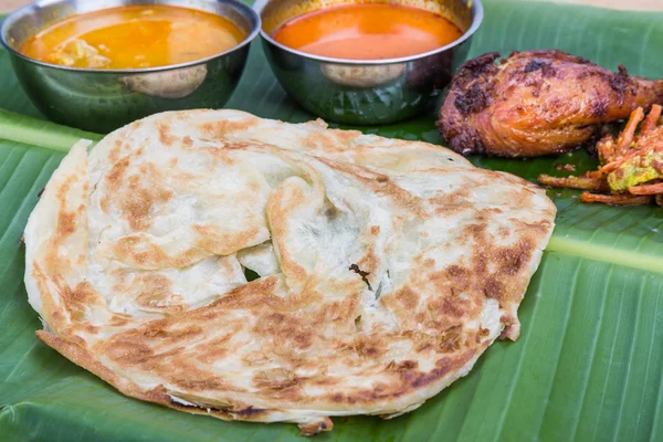 Traditional roti prata served on banana leaf with curry dhal. — Stock Photo, Image