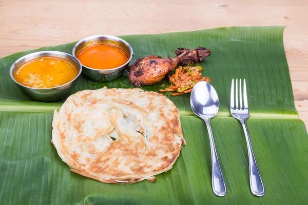 Traditional roti prata served on banana leaf with curry dhal. — Stock Photo, Image