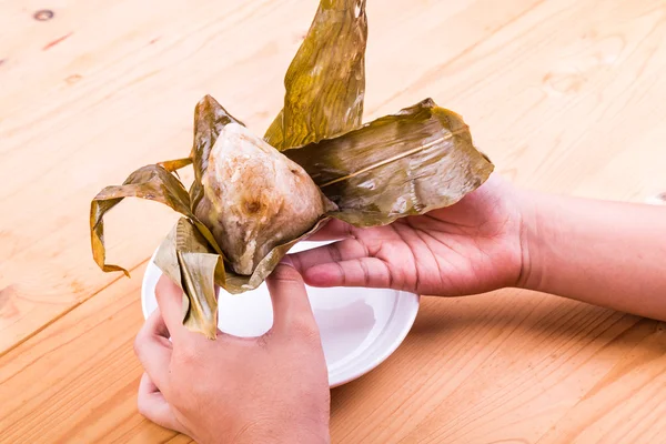 Hand-Auspacken chinesischer Reisknödel oder Zongzi auf dem Tisch — Stockfoto