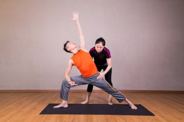 Yoga eğitmeni yol gösterici öğrenci gerçekleştirmek genişletilmiş yan açı poz
