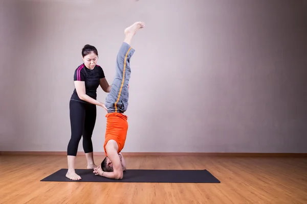 Yoga instructeur leidende student uitvoeren hoofd stand pose of Sirsa — Stockfoto