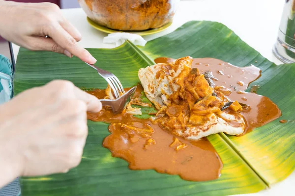 Person som äter roti canai eller paratha serveras med curry serverad på bananblad — Stockfoto