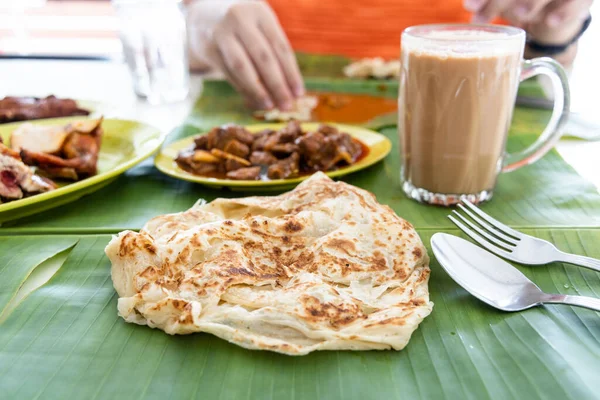 Roti canai atau paratha disajikan di daun pisang, dengan kari kambing dan ayam goreng, dan teh tarik yang populer — Stok Foto