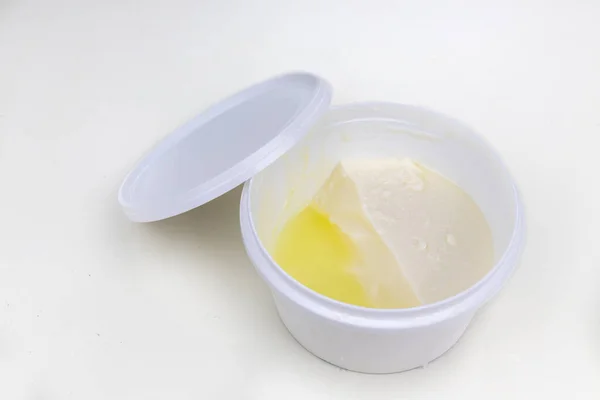 Слой сывороточного белка сформировался поверх упакованного йогурта после открытия на белом фоне. — стоковое фото