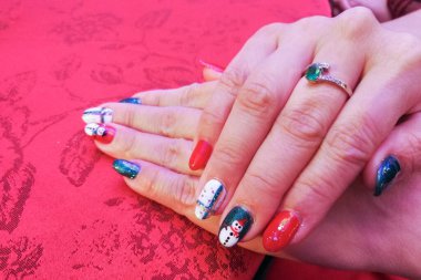 Manikürlü akrilik tırnaklar. Kırmızı arka planda güzel renkli tırnak sanatı.