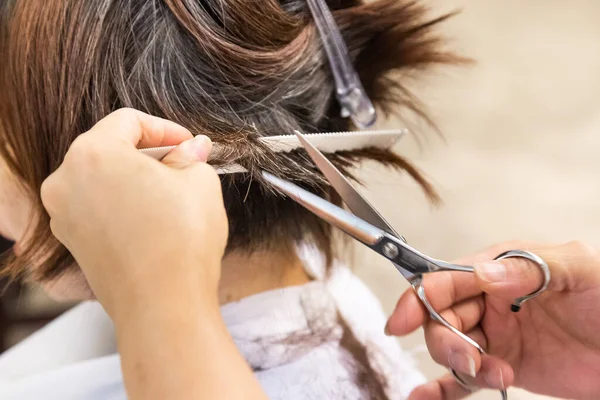 Close-up of hair dresser barber cutting hair of female client with scissors and comb — Stock Photo, Image