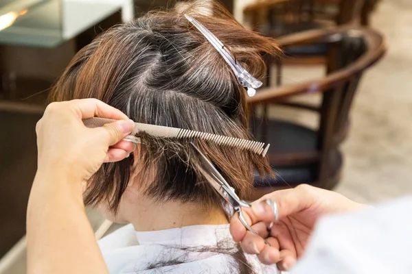 Close-up of hair dresser barber cutting hair of female client with scissors and comb — Stock Photo, Image