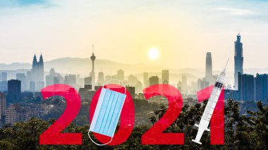 2021 'de Kuala Lumpur şehir manzarasına karşı yazılmış yüz maskesi ve şırıngası ile Covid-19 aşı yılı