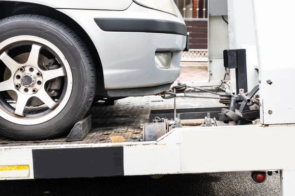 Broken down car towed onto flatbed tow truck