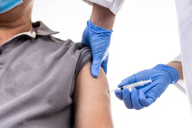 Asyalı orta yaşlı adamın koluna Covid-19 aşısı vurulurken yakın plan çekimde.