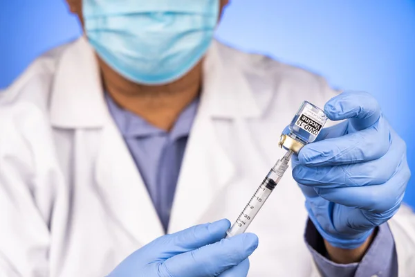 Close-up and focus on syringe inserted into Covid-19 vaccine vial by Asian medical doctor with medical glove in background — Stock Photo, Image