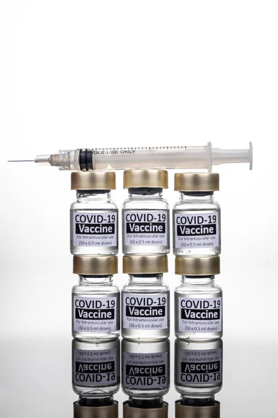 Beberapa botol vaksin Covid-19 dengan konsep jarum suntik pada permukaan reflektif — Stok Foto