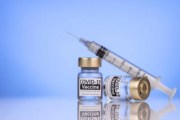 Sprøjte hviler på Covid-19 vaccine hætteglas koncept med reflekterende overflade Stock-foto