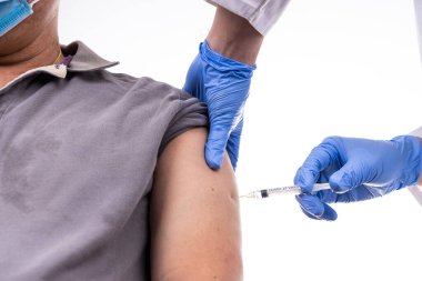 Asyalı orta yaşlı adamın koluna Covid-19 aşısı vurulurken yakın plan çekimde.