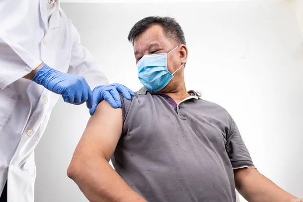 Asian middle age man receiving Covid-19 vaccine injection onto the arm — Stock Photo, Image