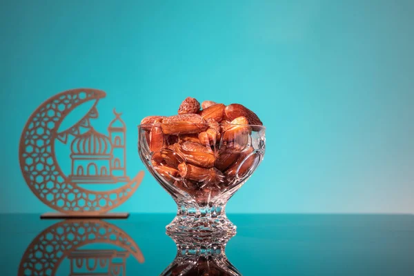 Muslim iftar of breaking of fast during Ramadan month with preserved sweet dates.. Decorative crescent and mosque in background as prop — Stock Photo, Image