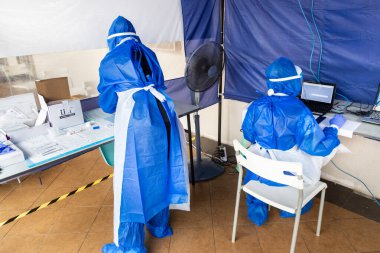 Tam teşekküllü kişisel koruma teçhizatında sağlık çalışanı açık hava covid-19 test merkezini yönetiyor.