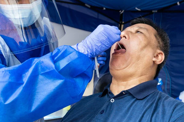 Maduro asiático hombre haciendo covid 19 PCR hisopo prueba a través de la garganta —  Fotos de Stock