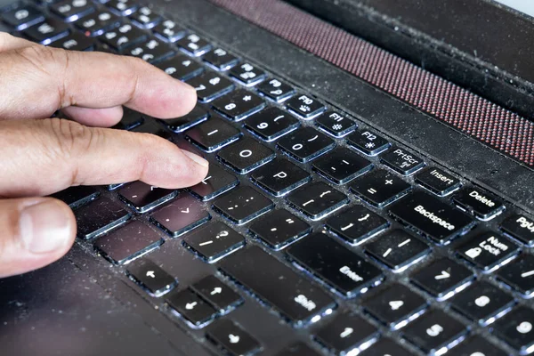 Fingers typing on laptop computer keyboard laced with dusk, particles and is very unhygienic and unhealthy