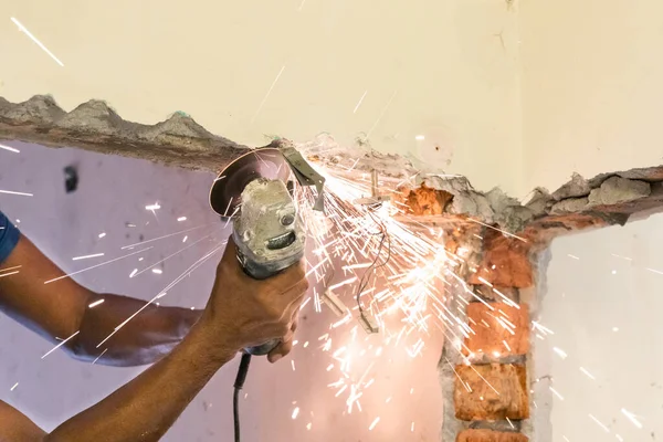 Arbeiter schneidet Betonwand mit Scheibenschneidwerkzeug, dabei entstehen Funken — Stockfoto