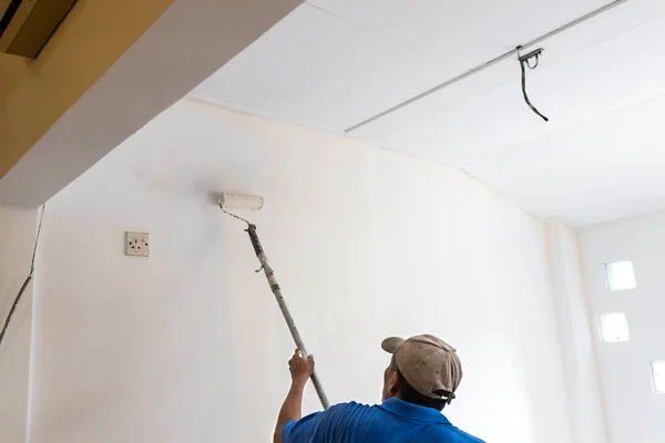 Parede da pintura do trabalhador com revestimento da pintura usando o rolo da pintura — Fotografia de Stock