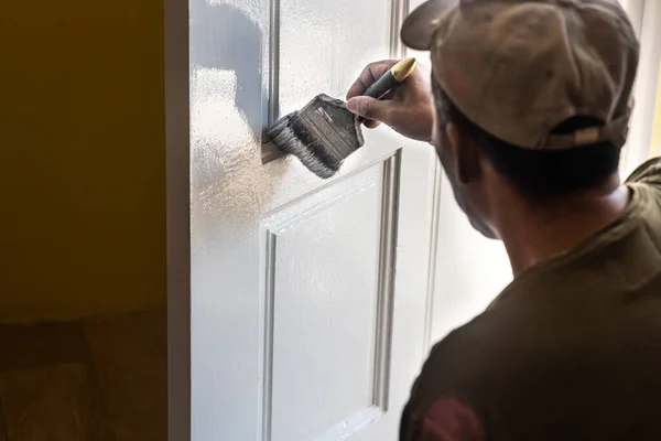 在房屋出租过程中，有人用油漆刷在木制的白色门上作画。运动模糊原意. — 图库照片