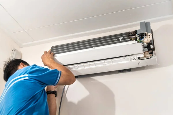 Technician installing indoor air conditioner condenser unit on wall