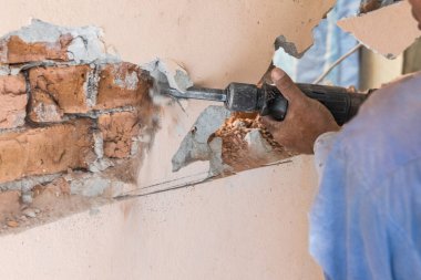 İşçiler duvar yüzeyini kırmak için yıkım çekiç matkabı kullanıyor. Hareket bulanıklığı amaçlandı.
