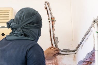 Elektrikçi duvara gömülü plastik tüp içinde elektrik kablolarını gizliyor.