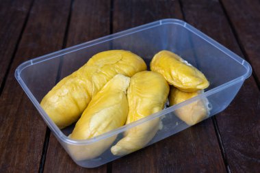 Altın sarısı musang kralı durian postu kabın içinde ahşap yüzeyde