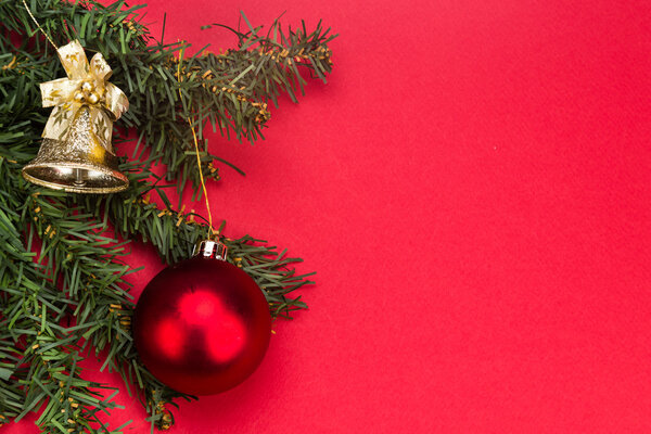 Простой красный рождественский фон с елкой, орнаментами и колоколом
