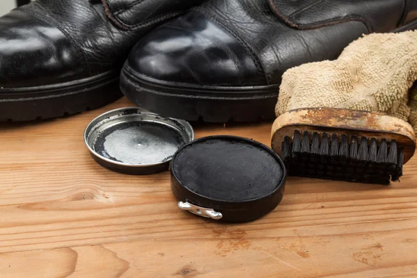 Schuhcreme mit Pinsel, Tuch und getragenen Stiefeln auf Holzplattform — Stockfoto