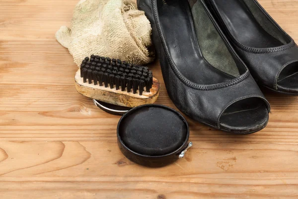 Shoe polish with brush, cloth and worn ladies court shoe on wood — Stock Photo, Image