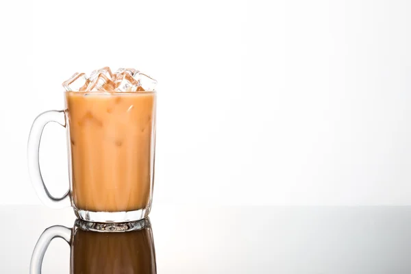 Verfrissend ijs koude thee met melk in transparant glas op witte achtergrond gespoeld links — Stockfoto