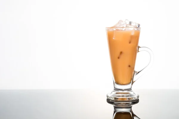 Refreshing ice cold tea with milk in transparent glass on dual tone background — Stock Photo, Image