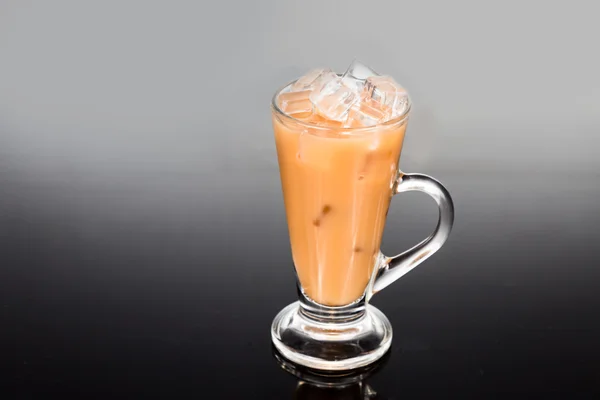 Refreshing ice cold tea with milk in transparent glass on dual tone background — Stock Photo, Image