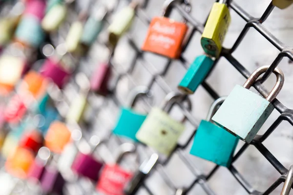 Muchos bloqueos de amor en concepto de valla con enfoque selectivo en una cerradura en blanco en primer plano — Foto de Stock