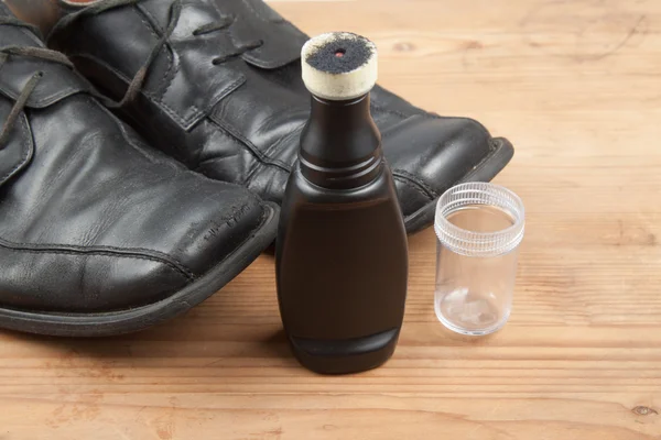 Convenient liquid shoe polish with worn out shoes on wooden plat — Stock Image Convenient liquid shoe polish with worn out shoes on wooden plat Stock Picture