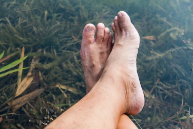 Bacaklar ve ayaklar önünde sakin taze su birikintisi rahatlatıcı